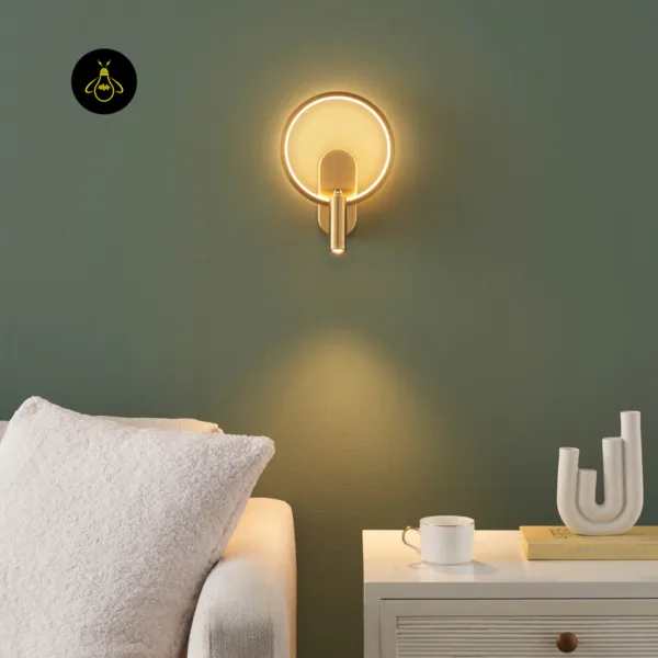 Gold circle wall light above a bedside table next to a sofa, spot lighting the table