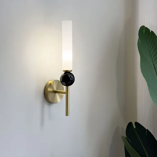Marble wall sconce at an angle beside a plant, showing the round backplate and side arm