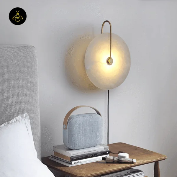 Plug in wall lamp with a gold arm beside a bed, glowing above a wooden bedside table