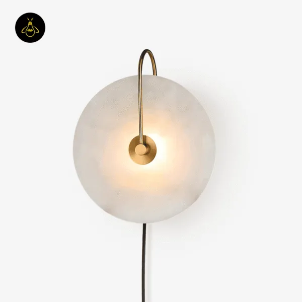 Gold plug in wall lamp glowing softly, alabaster disc with a curved stainless steel arm
