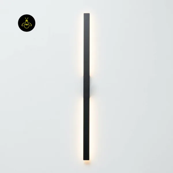 Slim LED wall light mounted vertically on a white wall, matte black stainless steel bar with a thin line of warm light behind it