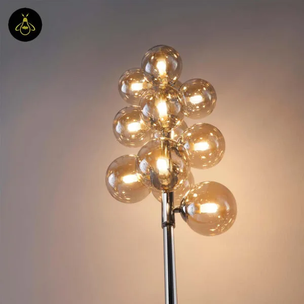Close-up of amber borosilicate glass globes on polished chrome floor lamp stem