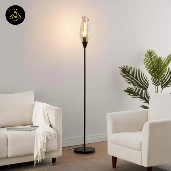 Black amber borosilicate glass floor lamp casting warm ambient light in a modern interior