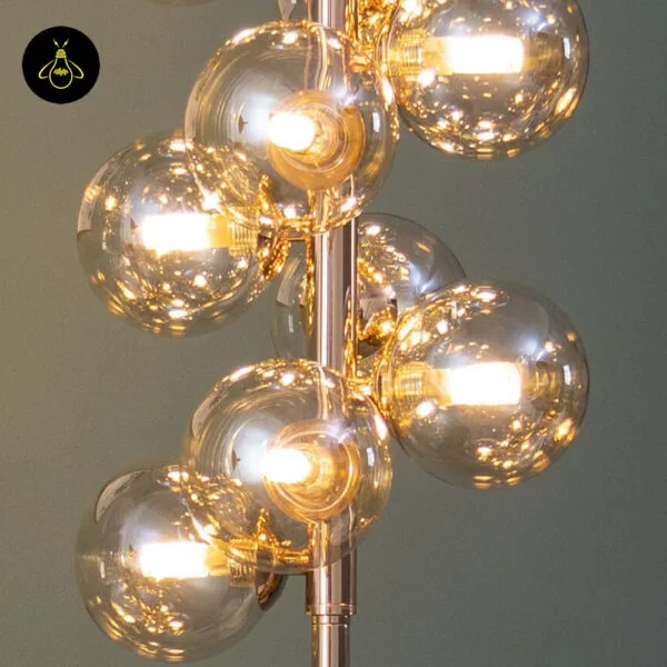 Close-up of the amber borosilicate glass globes and warm G9 bulbs on the gold floor lamp