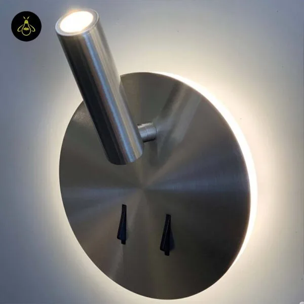 Wall lamp for bedroom with the reading spot turned upward and a warm halo around the brushed steel plate