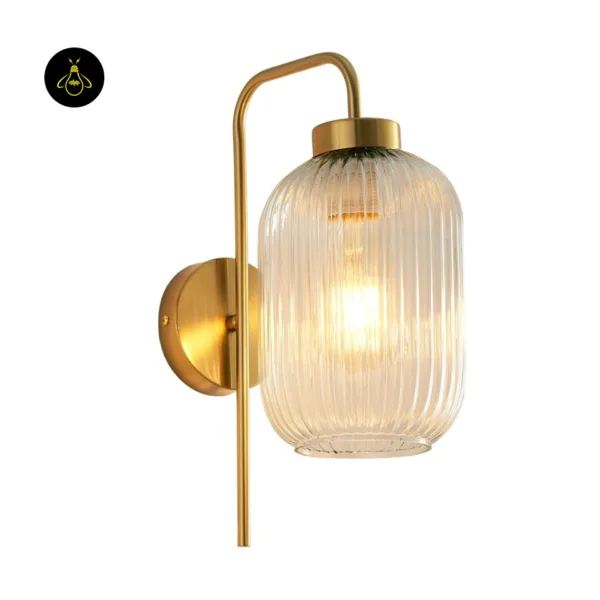 Fluted glass wall light on a white background, lit clear ribbed glass shade, brushed gold arm and round backplate
