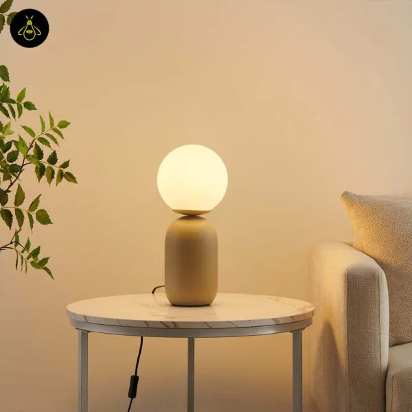Taupe table lamp with white globe and inline switch on a bedside table
