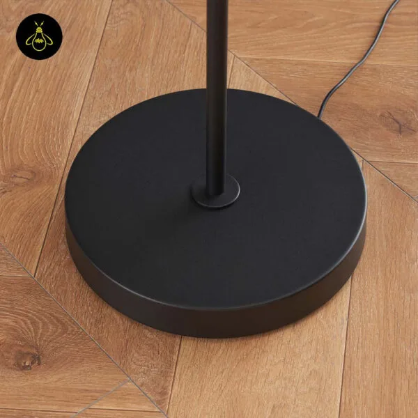 Black LED floor lamp with adjustable head adding warm light in a bedroom