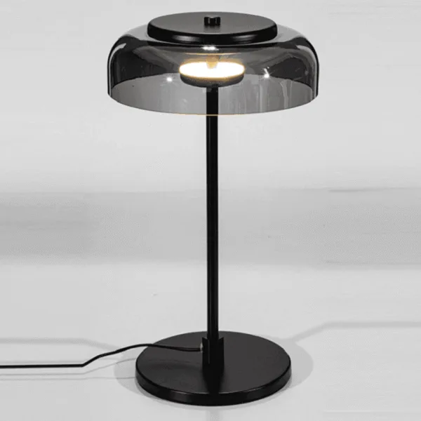 Black table lamp seen from above, its built-in warm LED glowing under the smoked borosilicate glass dome