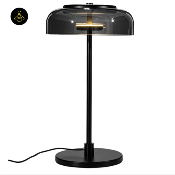 Black table lamp switched on, warm 3000K light glowing inside the smoked glass dome, cord running from the base