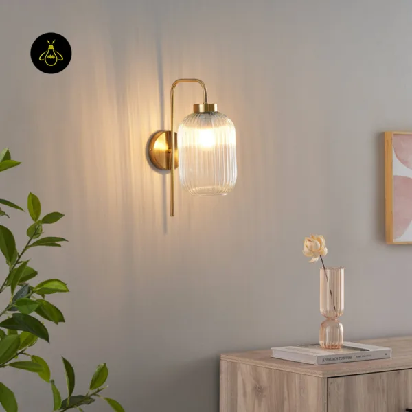 Fluted glass wall light glowing on a beige wall above a sideboard with a glass vase