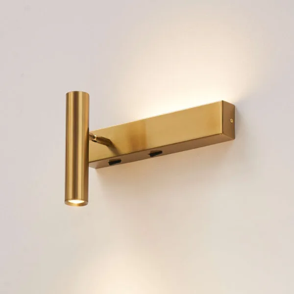 Satin gold wall reading lamp lit on a white wall, with two switches under the backplate