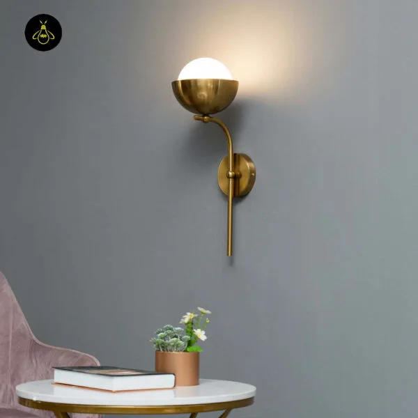 Opal white light lit on a grey wall above a marble side table with books and a potted plant