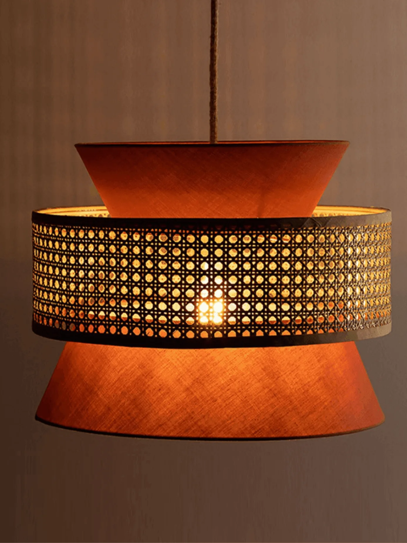 Cane & Fabric Layered Drum Pendant Light – 45 cm 6 Terracotta cane hanging light switched on, warm light glowing through the woven cane band and the cotton cones
