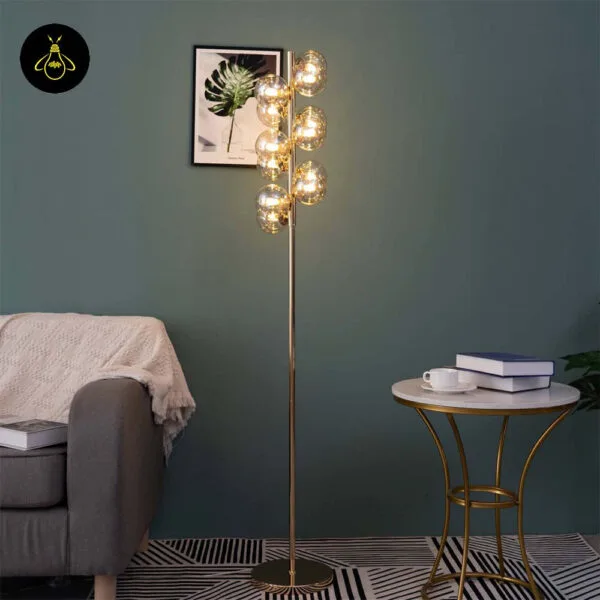 Gold floor lamp with amber borosilicate glass spheres beside a sofa and side table