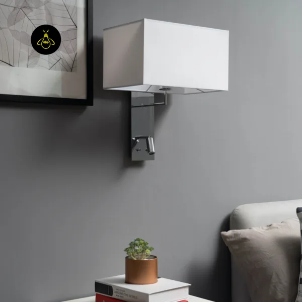 Wall mounted bedside light switched off beside a framed print above a bed
