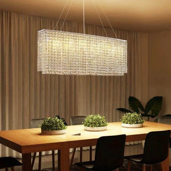 Oval crystal chandelier glowing warm over a long wooden dining table, curtains behind