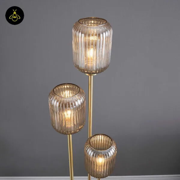Triple amber glass floor lamp lit with a warm amber glow in a living room