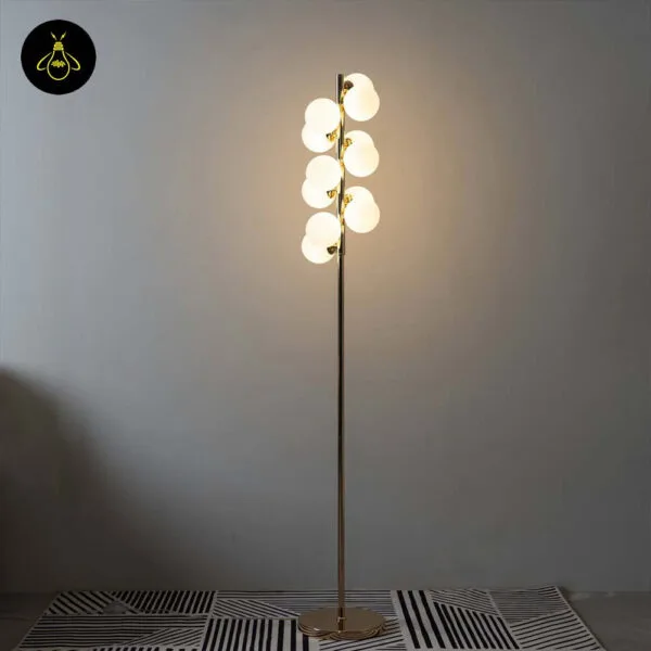 Close-up of white globe floor lamp showing opal-glass spheres on a polished gold frame