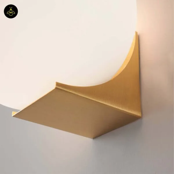 Detail of the folded brushed-gold stainless steel base of the globe wall light with the curved cut the globe rests in