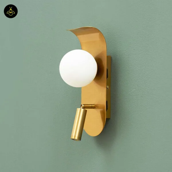 Side view of the bedroom reading light showing the curled top of the brushed gold leaf, the opal borosilicate glass globe and the reading spot