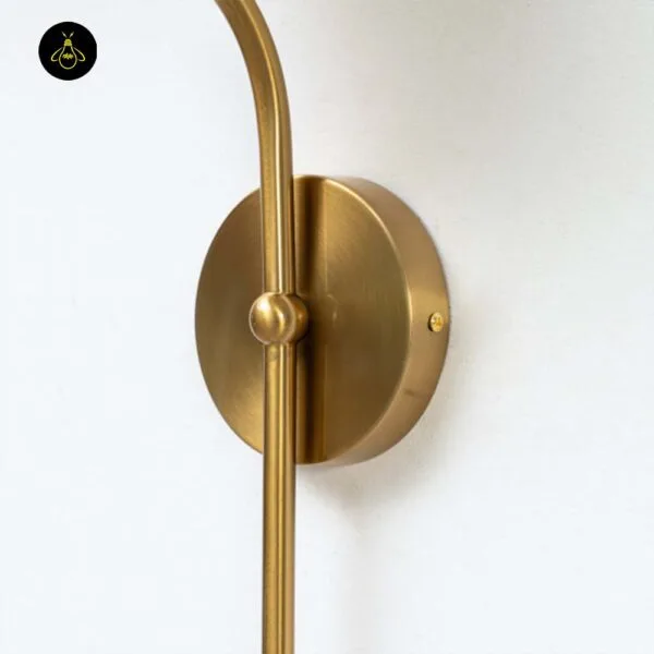 Opal white light backplate close-up: round brass-finish stainless steel plate with the curved stem