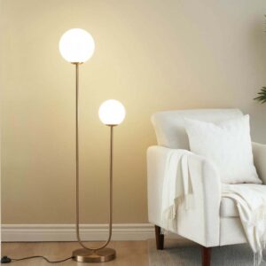 Brass dual globe floor lamp with white opal glass beside a lounge chair