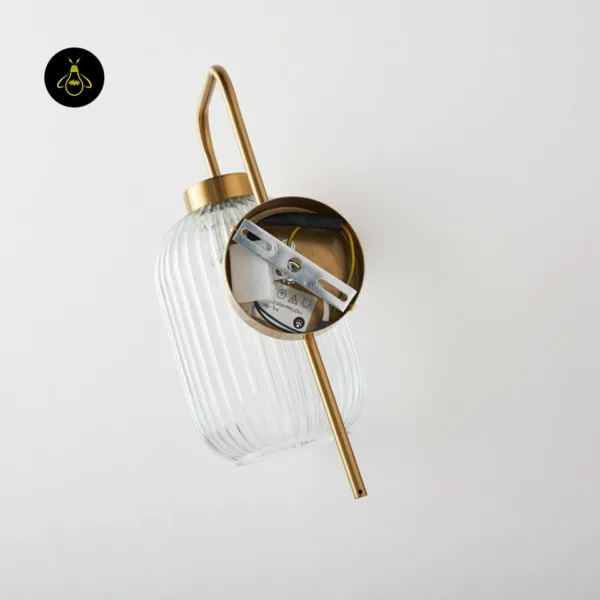 Back of the fluted glass wall light showing the round gold backplate and mounting bracket