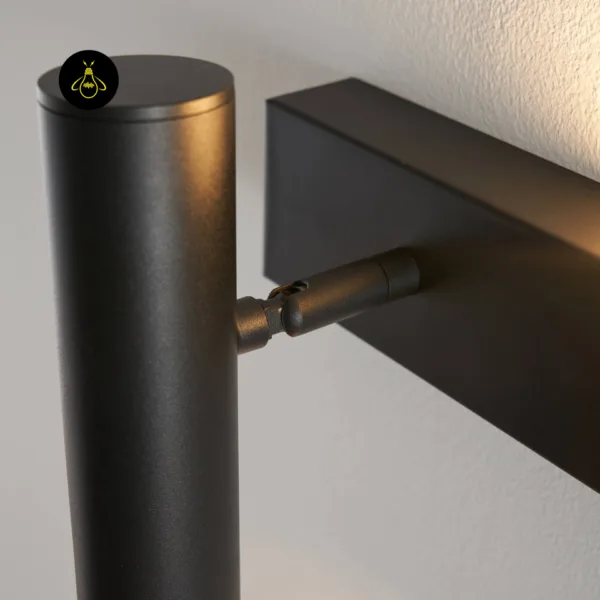 Close-up of the pivot joint linking the reading head to the backplate on the black wall reading lamp