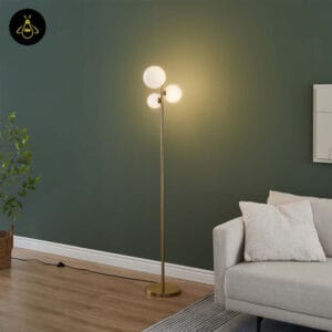 Glass globe floor lamp glowing warm against a deep green wall beside a sofa