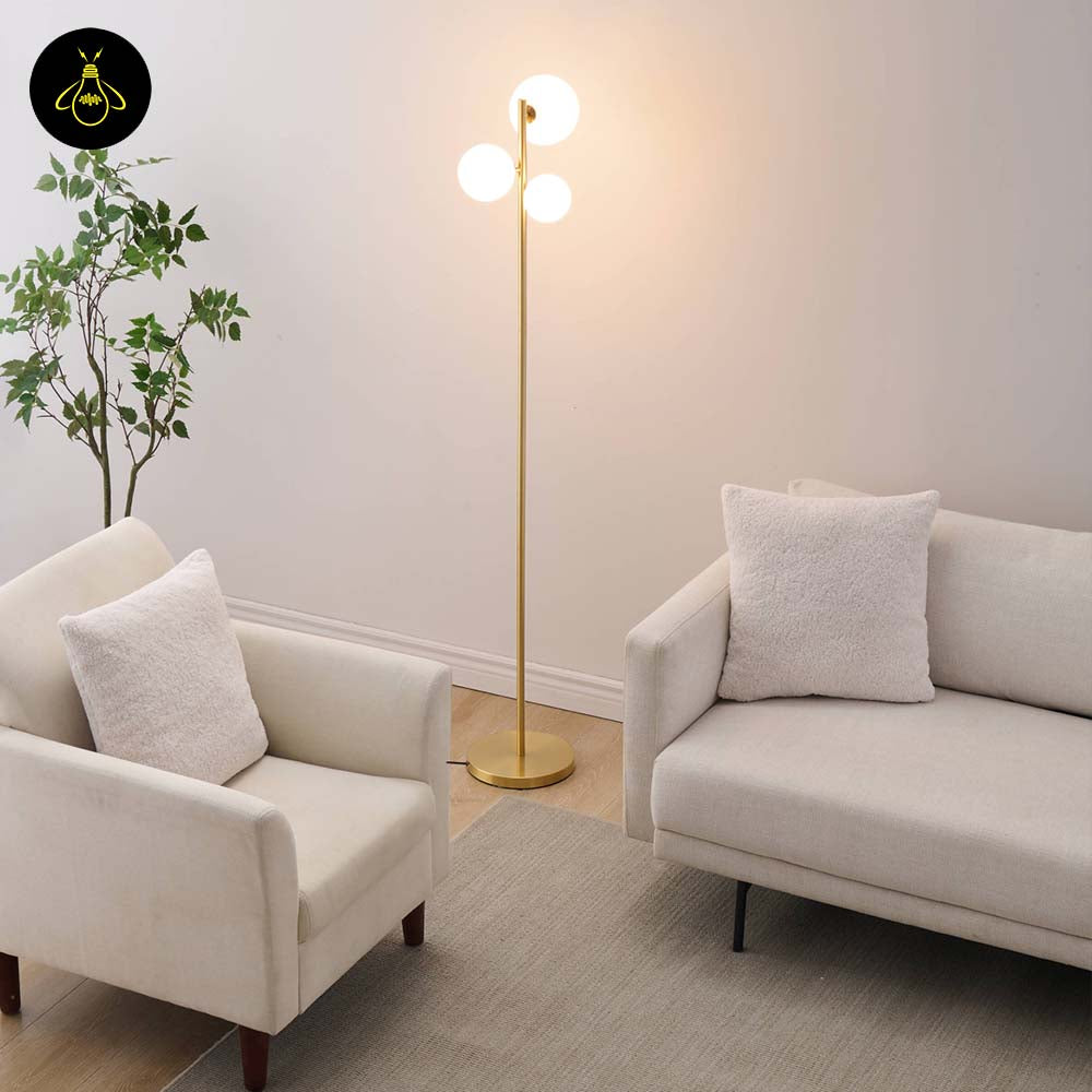Gold floor lamp with white glass spheres creating soft ambient light beside modern seating