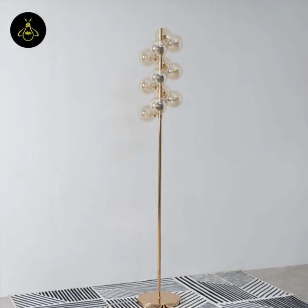 Gold floor lamp with amber borosilicate glass spheres shown in packaging-style full view