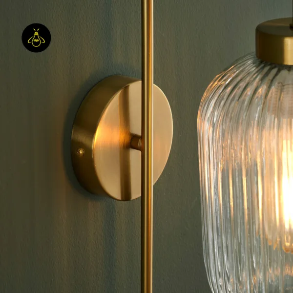 Detail of the fluted glass wall light: brushed gold round backplate, slim rod and ribbed glass shade