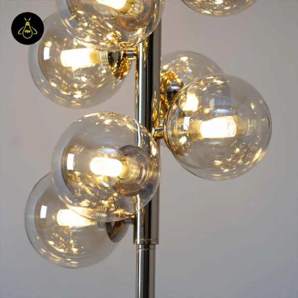 Gold floor lamp with amber borosilicate glass spheres styled in a bedroom corner