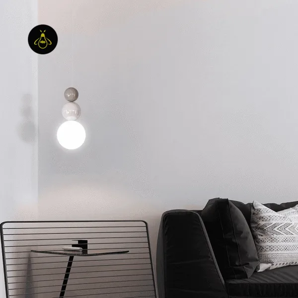 Glass ball pendant light lit beside a dark sofa in a grey living room