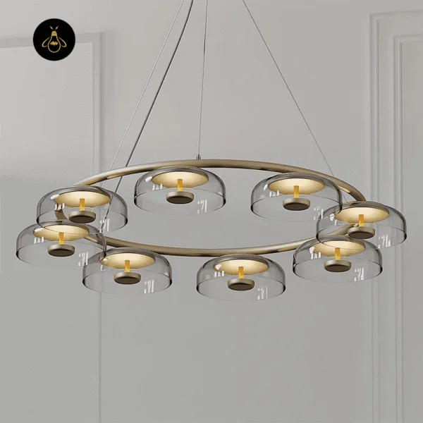 Glass dome chandelier lit against a grey panelled wall, eight clear domes glowing on the brass-finish ring