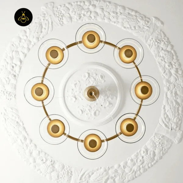 Glass dome chandelier seen from below, eight glowing domes in a circle under a white plaster ceiling medallion