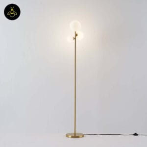 Full-length gold glass globe floor lamp with three white opal spheres on a white background
