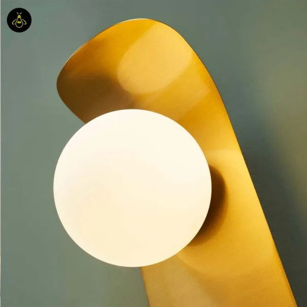 Close-up of the opal borosilicate glass globe on the brushed gold 304 stainless steel leaf of the bedroom reading light