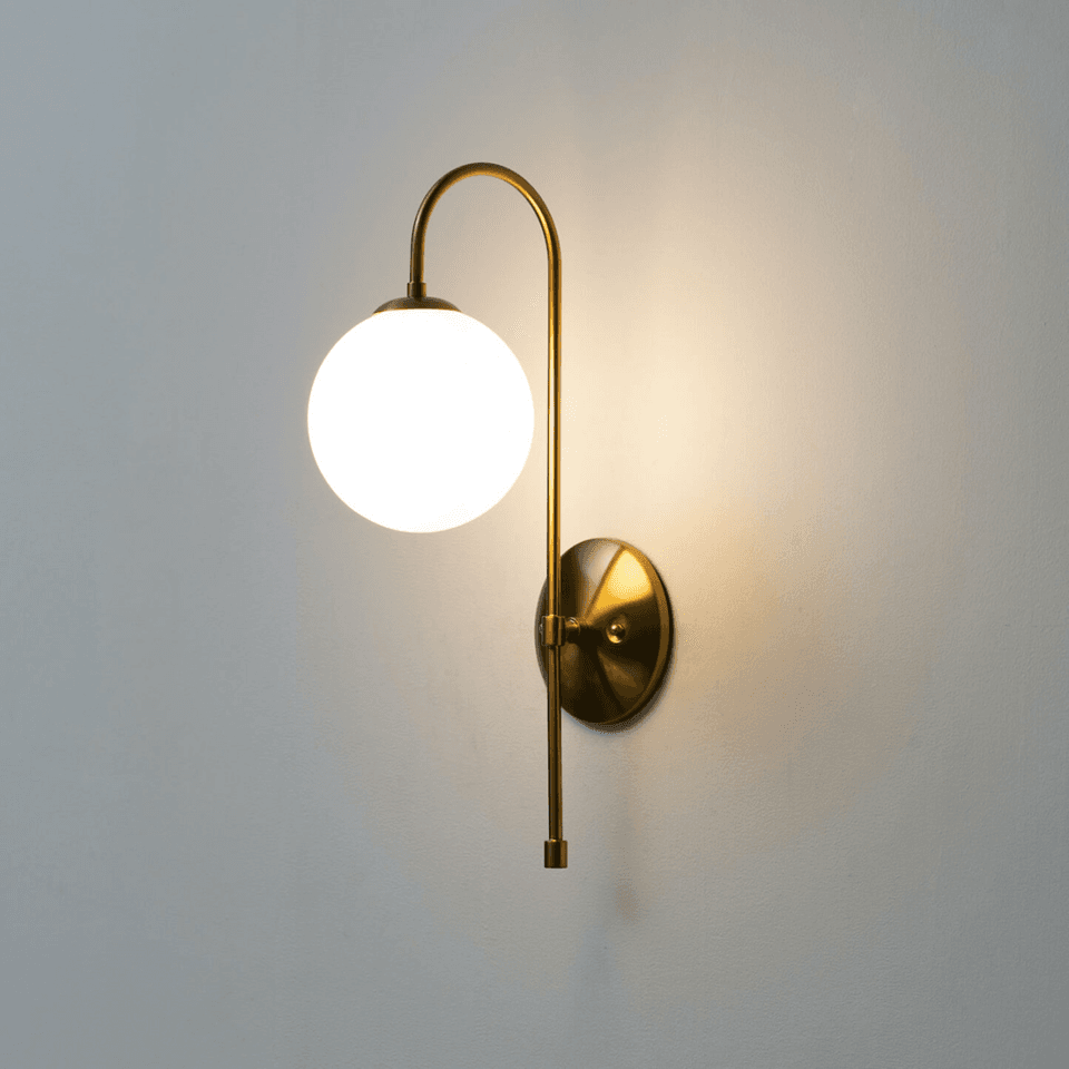 Gold wall light for living room with white frosted glass globe on a vintage-gold arched arm