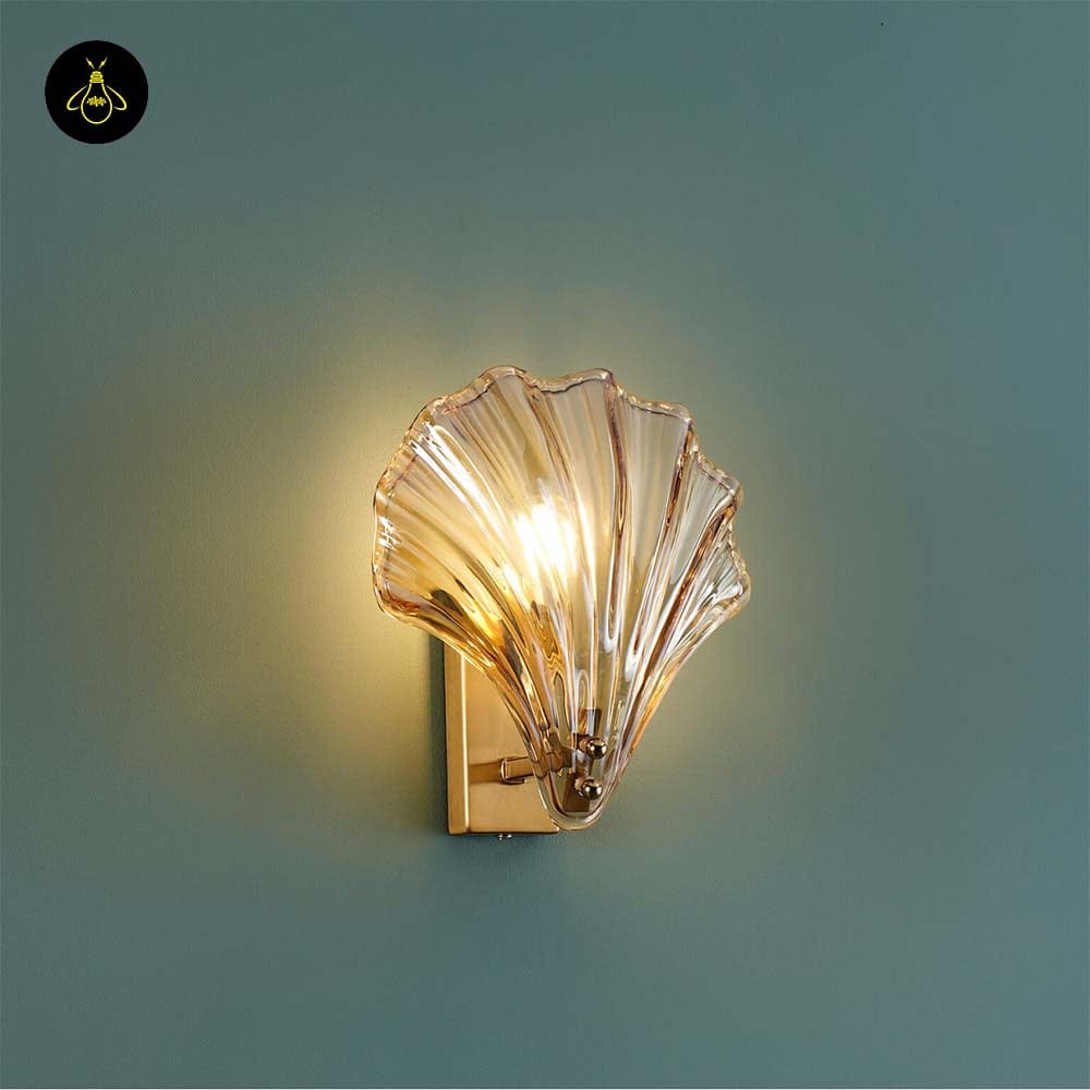 Gold shell wall light with amber ribbed glass seashell shade glowing on a wall – Jagmag Lights