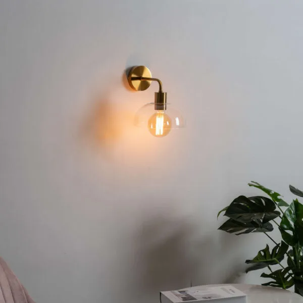 Dome wall light switched on above a living room side table, warm glow on a white wall