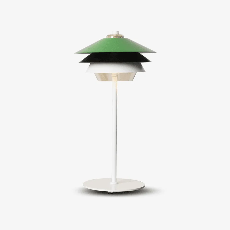 Green table lamp with green, black and white steel tiers over a clear glass diffuser, on a white stem and base