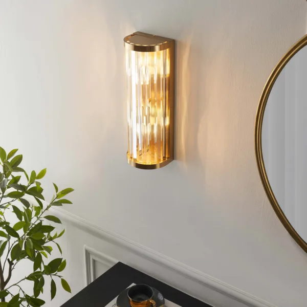 Angled view of a glowing ribbed glass wall light beside a round mirror and a potted plant