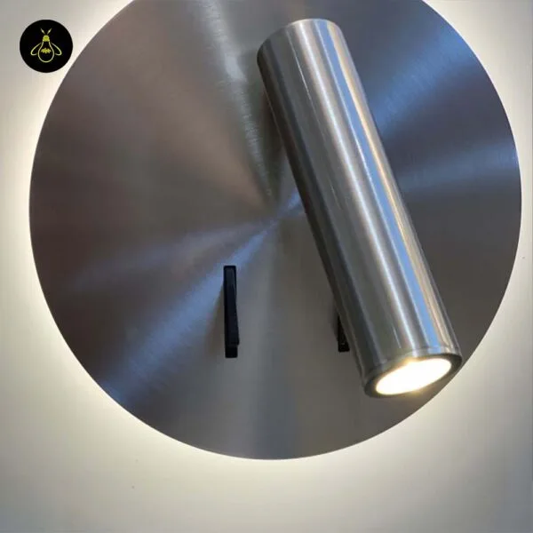 Wall lamp for bedroom with the reading spot angled down over the brushed 304 stainless steel disc, halo lit