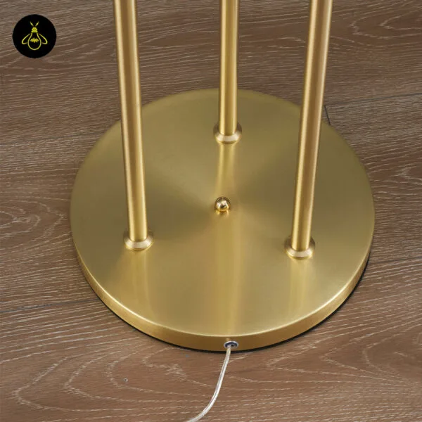 Triple amber glass floor lamp with gold frame standing beside a sofa