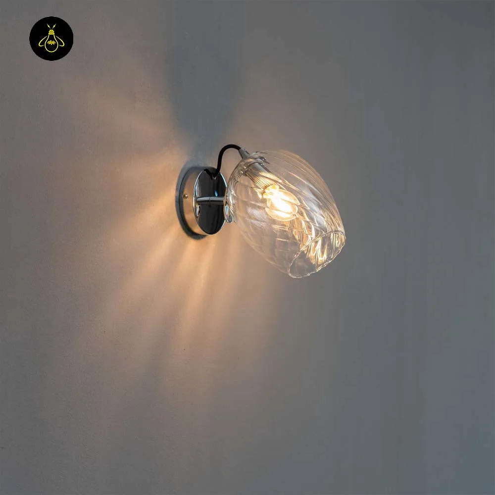Textured glass wall light with clear swirled shade and chrome finish, lit on a wall