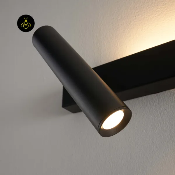 Close-up of the black wall reading lamp reading head with the warm LED switched on