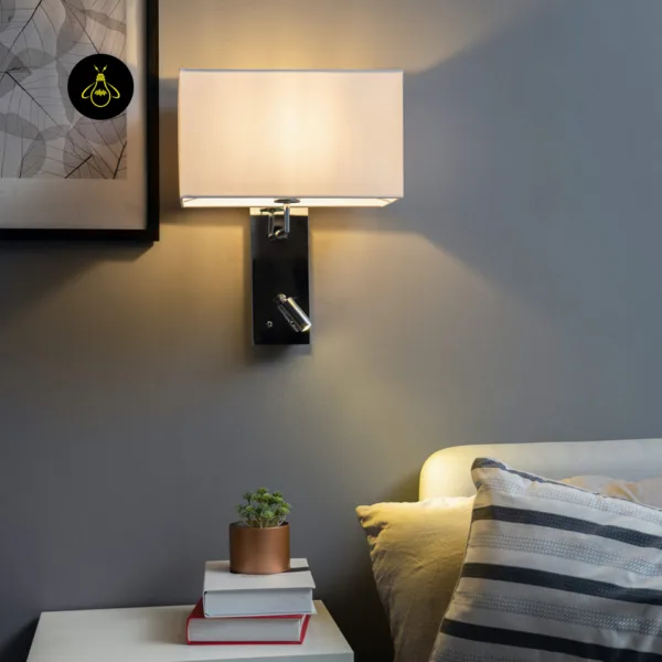 Wall mounted bedside light lit beside a bed with striped cushions and a nightstand
