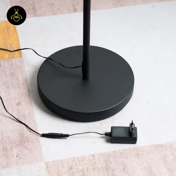 Round base of black LED floor lamp with reading light and plug-in adapter